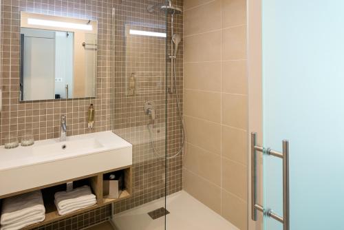 ein Bad mit einem Waschbecken und einer Dusche in der Unterkunft Hôtel Vitalparc in Lacanau-Océan