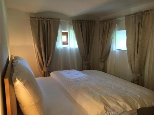 um quarto com uma cama branca e 2 janelas em Naturresidenz Kropfitsch em Krumpendorf am Wörthersee
