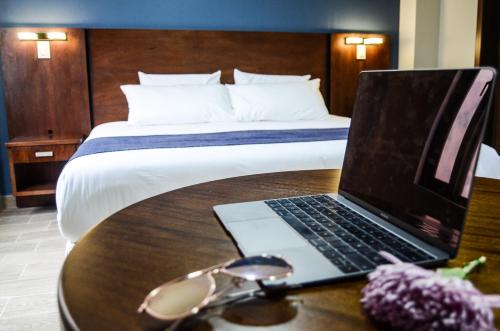 a laptop on a table in a hotel room with a bed at Hotel San Agustin Plaza in Latacunga
