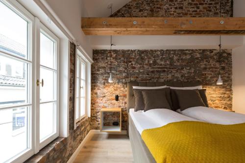 سكوير روومز 20 في دوسلدورف: غرفة نوم بحائط من الطوب وسرير اصفر