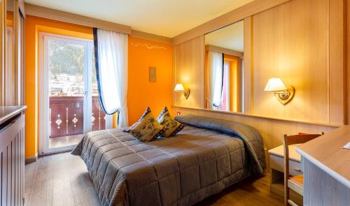 a bedroom with a bed and a large window at Hotel La Serenella in Moena