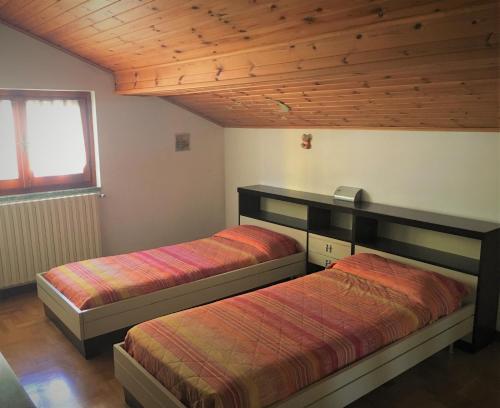 two beds in a room with wooden ceilings at Appartamento Gorgotto in Gravedona
