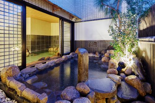 une piscine d'eau avec des rochers devant un bâtiment dans l'établissement Dormy Inn Kurashiki Natural Hot Spring, à Kurashiki