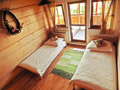 two beds in a room with wooden floors and windows at Pokoje u Kalaty in Szaflary