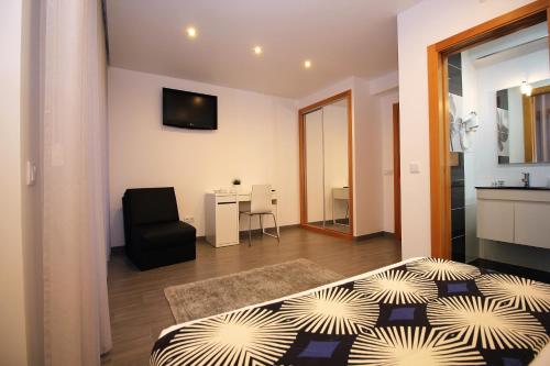 a bedroom with a bed and a chair in a room at Gaivota Holidays in Nazaré