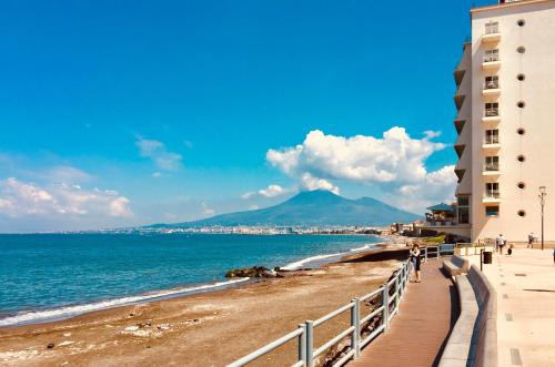 einen Strand mit Gebäuden und dem Meer und einem Berg in der Unterkunft lungomare rooms in Castellammare di Stabia