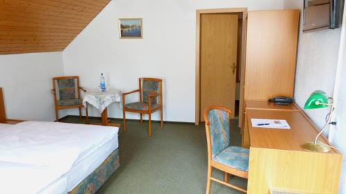 a room with a bed and a table and chairs at Hotel Mühlenhof in Heidenau