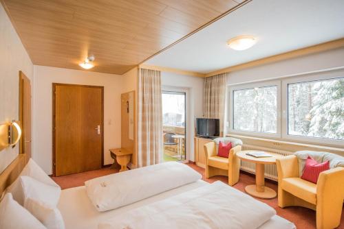 Habitación de hotel con cama, mesa y sillas en Hotel Garni Waldhof - Wohlfühlen am Lech, en Stanzach