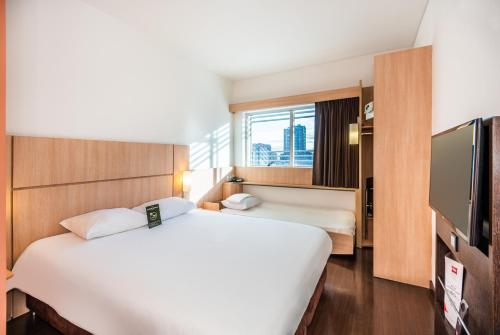 a hotel room with two beds and a flat screen tv at ibis Bogota Museo in Bogotá