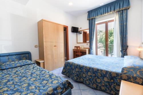 a hotel room with two beds and a window at Hotel La Pergoletta in SantʼAgata sui Due Golfi