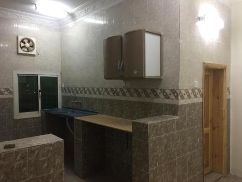 a tiled kitchen with a sink and a mirror at Wahat Al Yarmouk Serviced Apartments in Ţubarjal