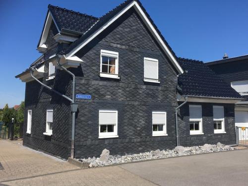 a black house with white windows on a street at Ferienhaus Pacco in Wermelskirchen