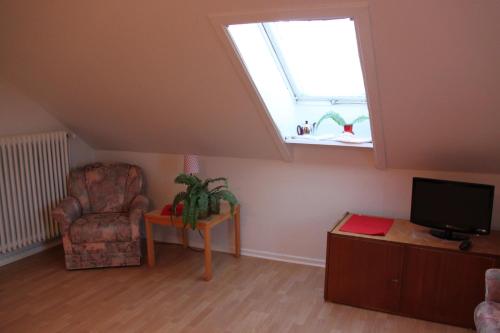 a living room with a window and a chair and a tv at Haus Marinus in Puttgarden