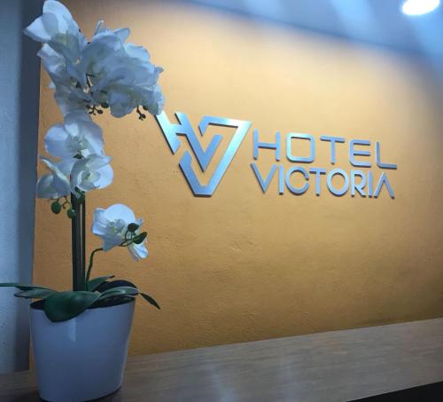 un jarrón con flores blancas delante de un cartel de hotel en Hotel Victoria, en Monterrey