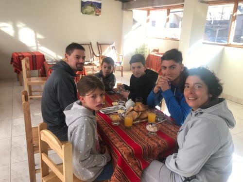un grupo de personas sentadas en una mesa comiendo comida en Hostal Apu Qhawarina en Ollantaytambo