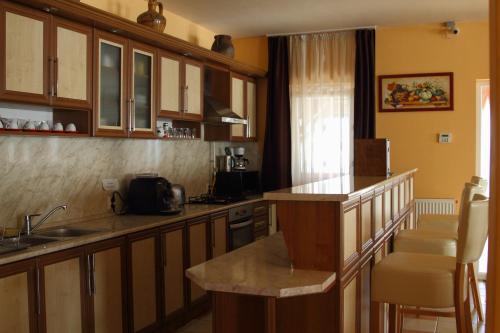 a kitchen with wooden cabinets and a counter top at Viktor Vendégház és Apartmanház in Baktalórántháza