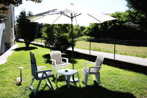 un gruppo di sedie e un ombrellone nell'erba di Casamia B&B a Castelletto sopra Ticino