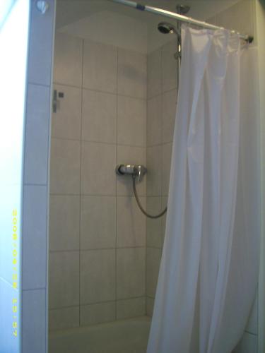 a shower with a white shower curtain in a bathroom at Haus Marinus in Puttgarden