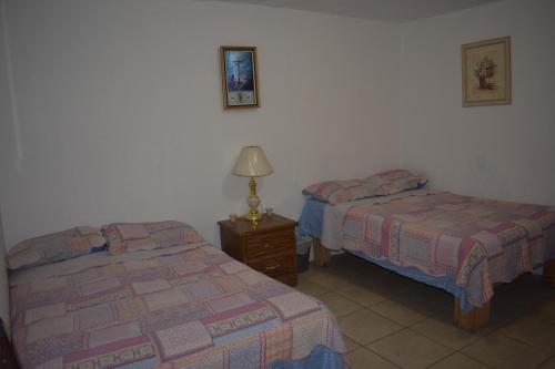 Un dormitorio con dos camas y una lámpara sobre una mesa. en Blanquita guesthouse, en Manuel F. Martínez