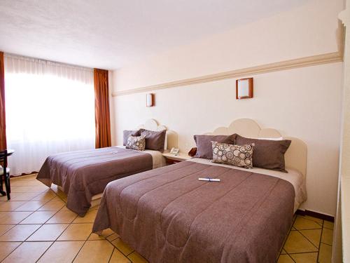 a hotel room with two beds and a window at Hotel 9 Manantiales in Chignahuapan