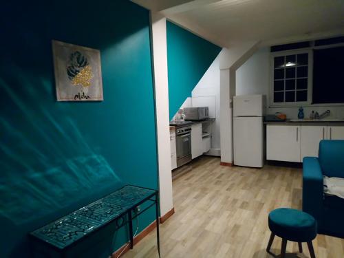 a living room with a blue wall and a kitchen at L'apparté enchantée in Schœlcher