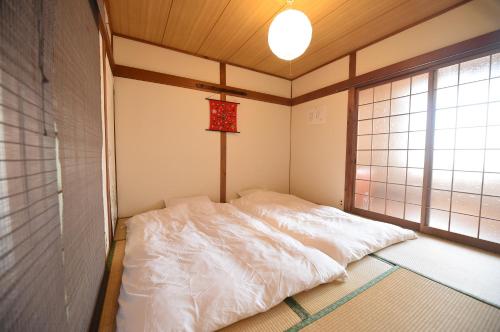 una camera con letto bianco in una stanza con finestra di Meguli a Kyoto