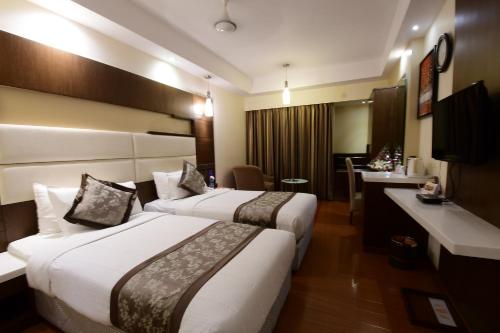 a hotel room with two beds and a desk at Hotel Daspalla in Visakhapatnam