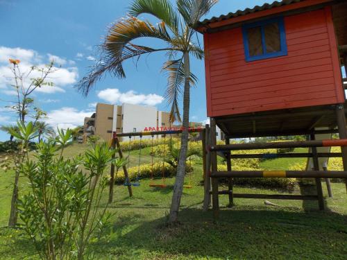 a red house on a palm tree next to a building at Apartamento Eje Cafetero - Cerca Parque del Café - Tebaida in La Tebaida
