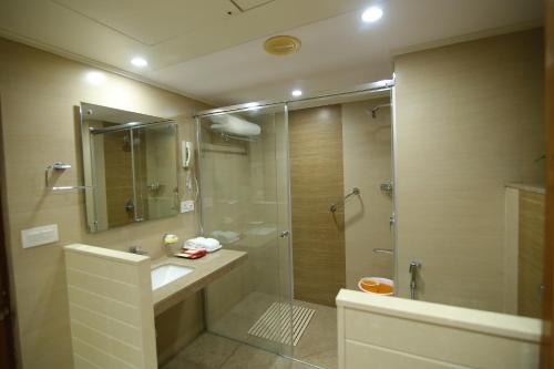 a bathroom with a shower and a sink and a glass shower stall at Hotel Daspalla in Visakhapatnam