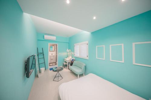 a bedroom with blue walls and a bed and a chair at Urban in Kaohsiung