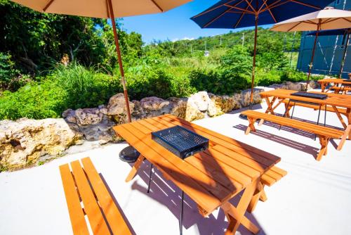 two picnic tables and umbrellas on a patio at Kourijima L'hotels in Nakijin