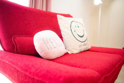 a red couch with two pillows on top of it at Kourijima L'hotels in Nakijin