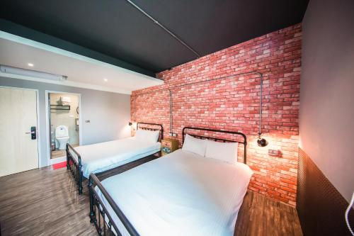 two beds in a room with a brick wall at Urban in Kaohsiung