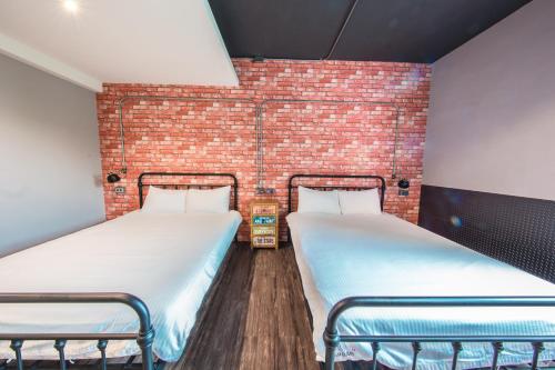 two beds in a room with a brick wall at Urban in Kaohsiung