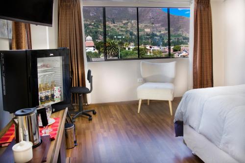 a hotel room with a bed and a chair and a window at Hotel California Calca in Calca