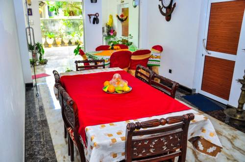 a red table with a plate of fruit on it at Rock Cascade tourist home in Polonnaruwa