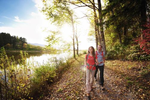 a man and a woman walking down a path by a lake at Hotel Natur-Landhaus Krone in Maierhöfen