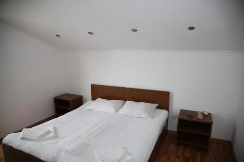 a bedroom with a white bed with two night stands at Merabi Guest House in Makhinjauri