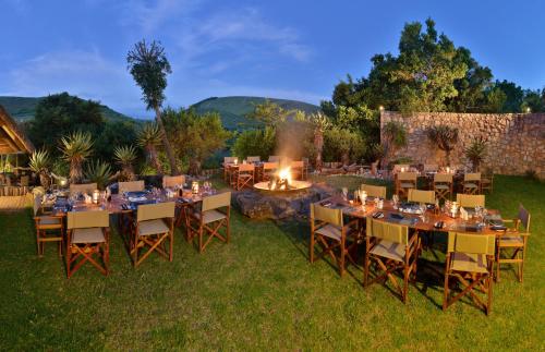 an outdoor dining area with tables and chairs and a fire pit at Shamwari Bayethe in Paterson