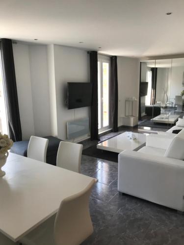 un soggiorno con mobili bianchi e TV di LE COEUR DE DEAUVILLE - 2 PIECES DESIGN EN HYPERCENTRE DE DEAUVILLE a Deauville