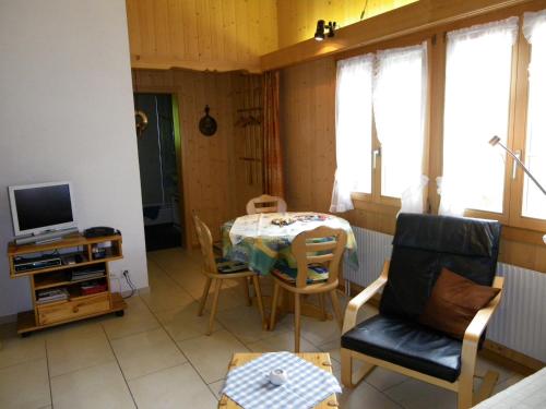 a living room with a table and chairs and a television at Am Eigen in Grindelwald