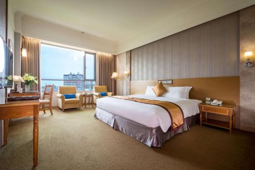 a hotel room with a large bed and a desk at Royal Chiayi Hotel in Chiayi City