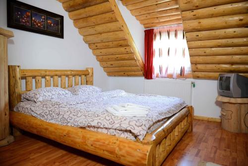 1 dormitorio con cama de madera y TV en la pared en Non Nobis Dambovicioara, en Dîmbovicioara