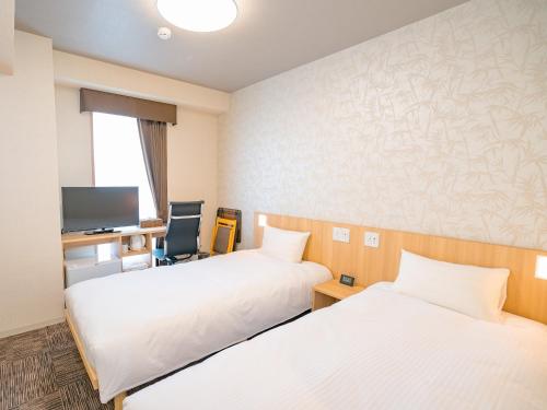 佐渡市的住宿－佐渡旅程酒店，酒店客房配有两张床和一张书桌