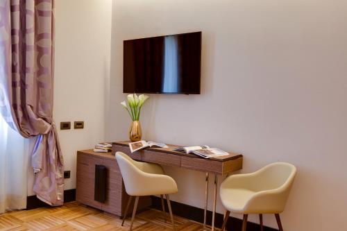 a desk with two chairs and a television on a wall at Solo Experience Hotel in Florence