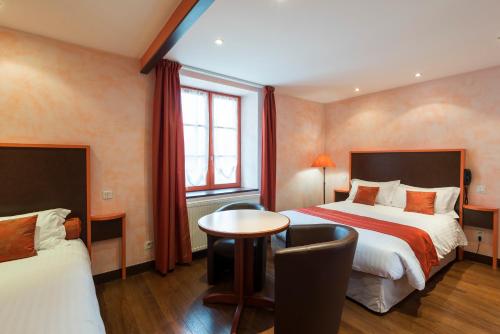 um quarto de hotel com duas camas e uma mesa em La Couronne em Jougne