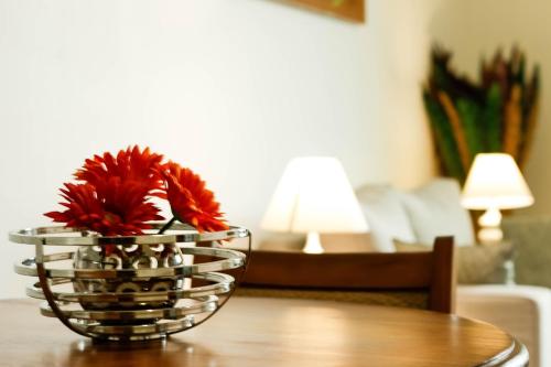 a vase with red flowers sitting on a table at Tchero Appartement 2 in Douala