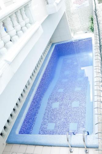 a large swimming pool in a white bathroom with a blue swimming poolvisor at Tchero Appartement 2 in Douala