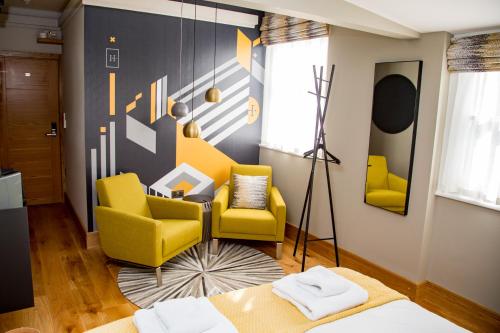 a living room with yellow chairs and a couch at The Hugo - Hotel Concept Canterbury in Canterbury