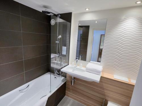 a bathroom with a tub and a sink and a mirror at Campanile Bordeaux Ouest - Mérignac Aéroport in Mérignac